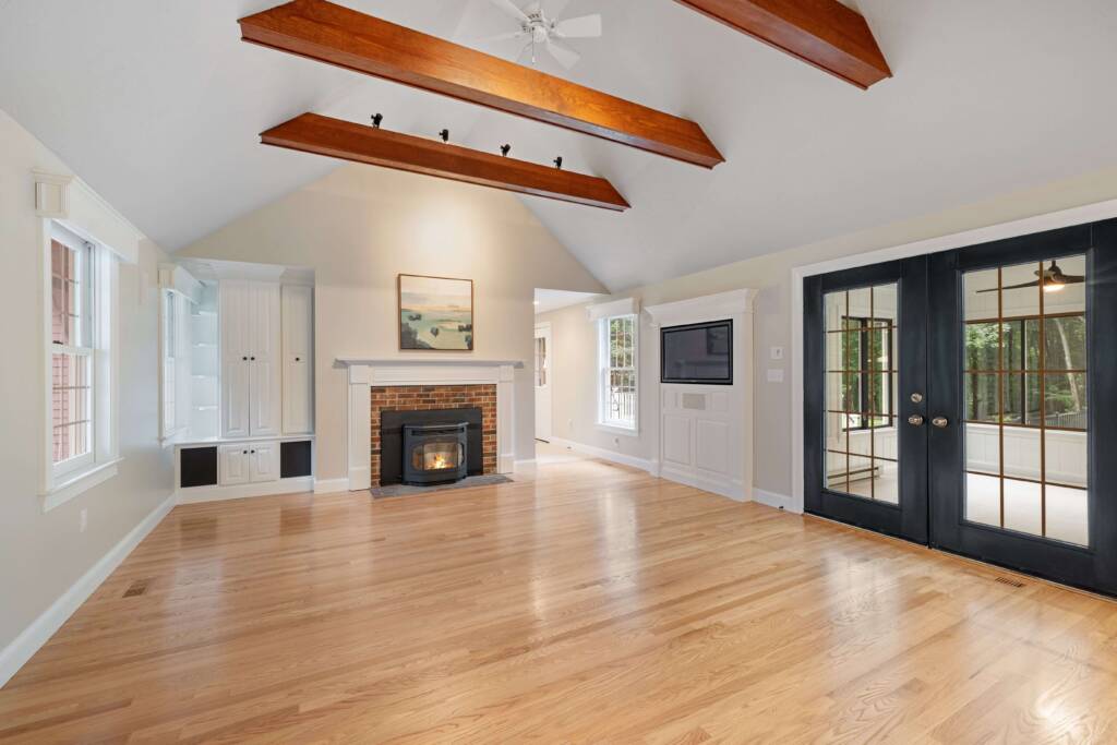 example of new home construction featuring elegant living room with vaulted ceilings, wood floors, open beams and french doors